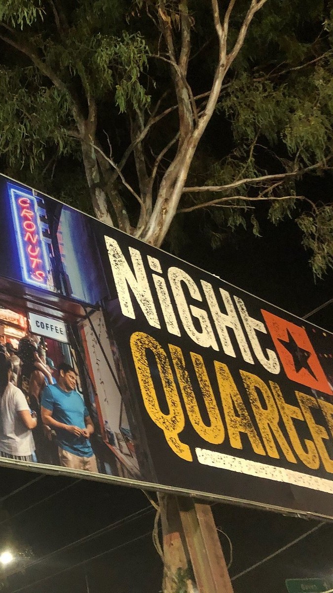 NightQuarter sign at night above the market crowd